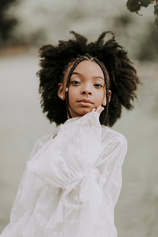 Confident kid in white outfit touching face